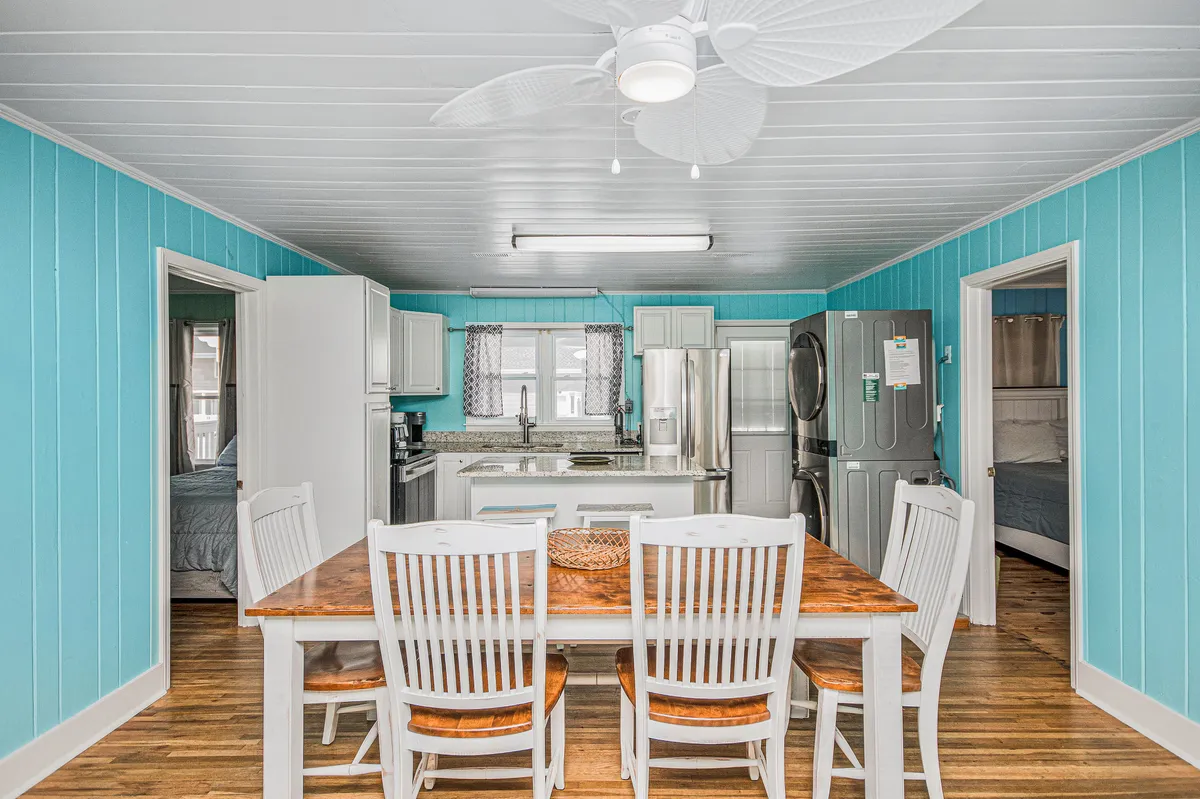 A view of the kitchen and adjoining dining area with a kitchen island, appliances, and blue walls. The image highlights the connection between cooking and dining, illustrating how guests can seamlessly transition from meal prep to shared dining experiences.
