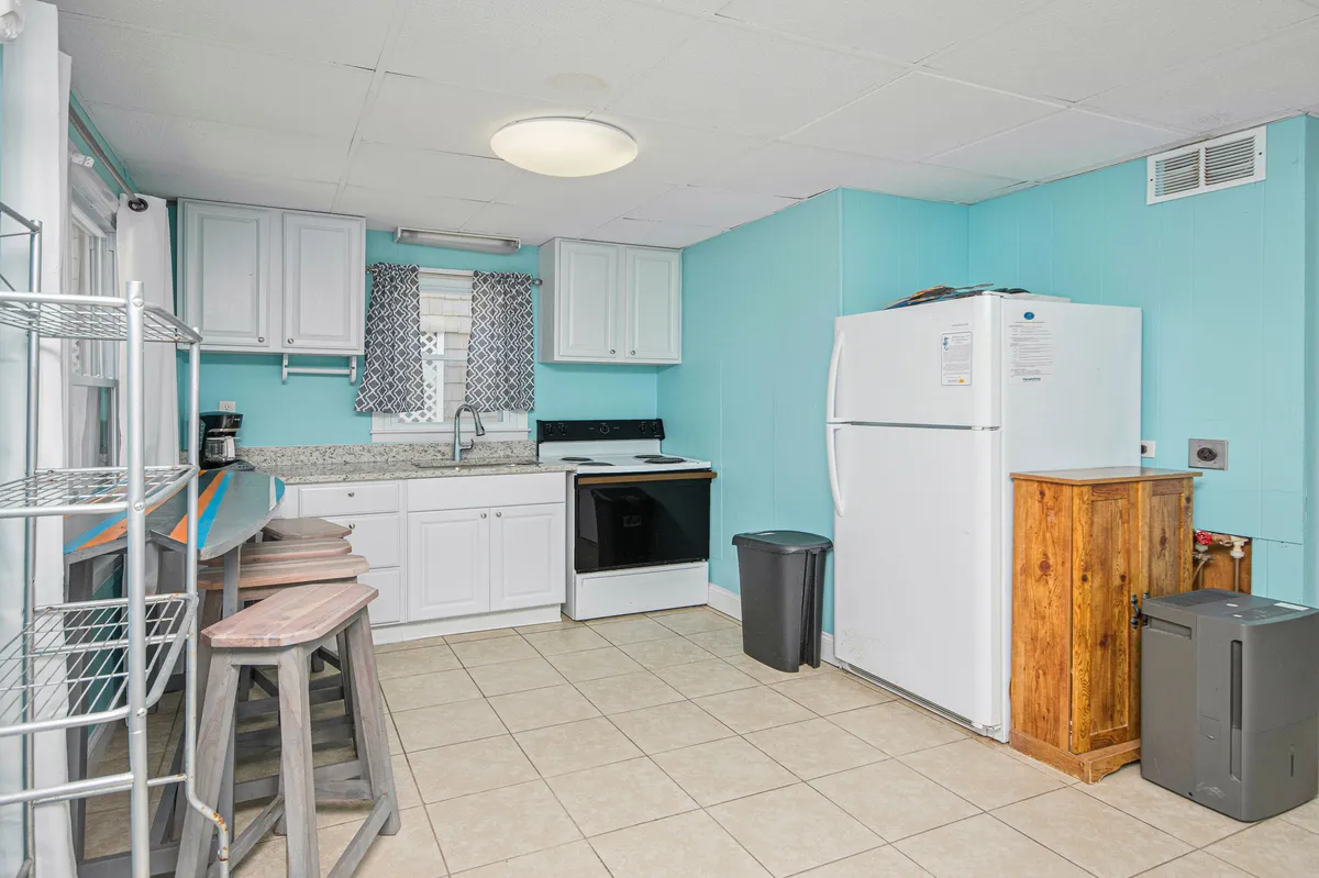 A welcoming kitchen and dining area featuring granite countertops, stainless steel appliances, blue walls, and wooden bar stools. This space is designed for both meal prep and casual gatherings, encouraging group participation.