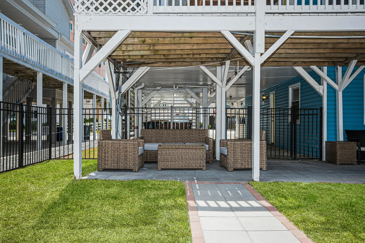 An inviting exterior shot showcasing a wicker seating area on a green lawn, with a stone pathway winding through. This tranquil vignette hints at peaceful outdoor moments and space for evening chats or sunbathing, completing the variety of private outdoor experiences.