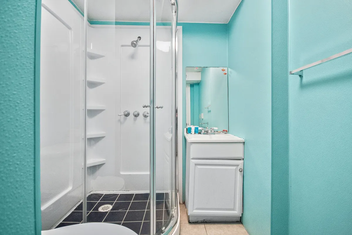 A modern bathroom featuring a shower enclosure, a vanity sink, and a mirrored wall. The space is well-lit, inviting, and designed for rejuvenation and self-care routines.